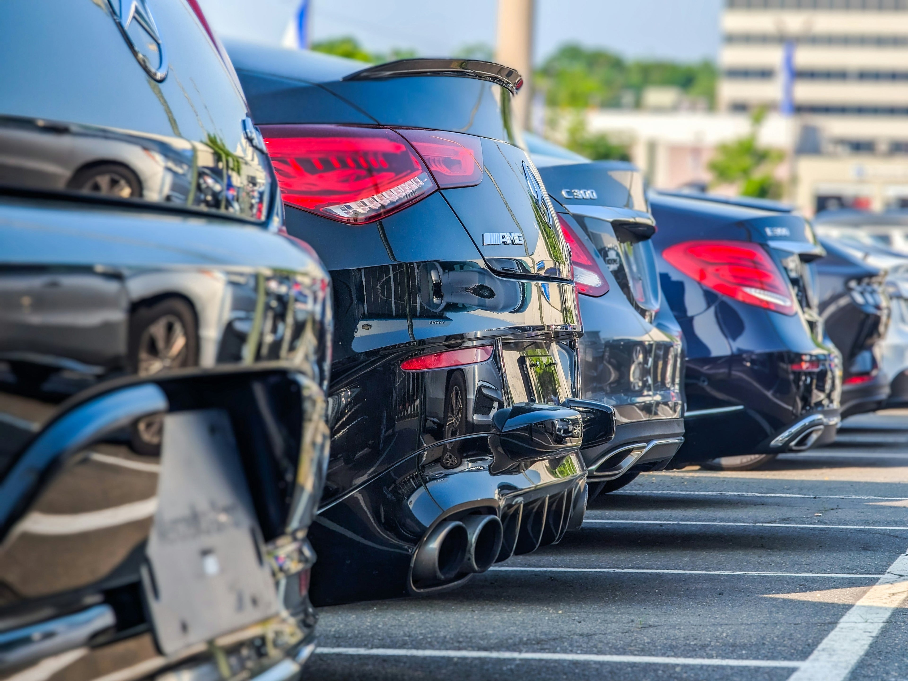 Row of black cars parked in a lot with a clear sky.