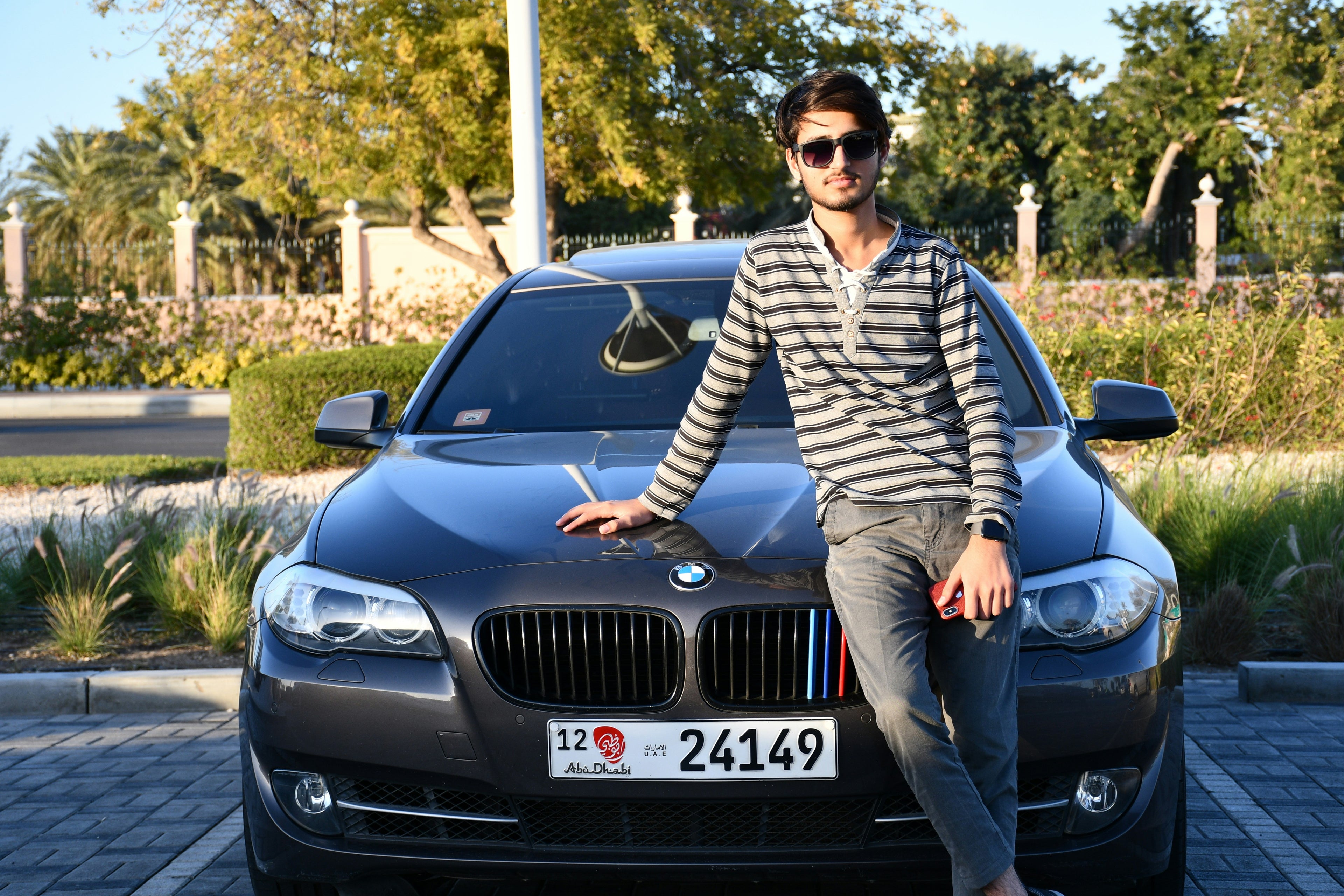 Man leaning against a black BMW car with a scenic background