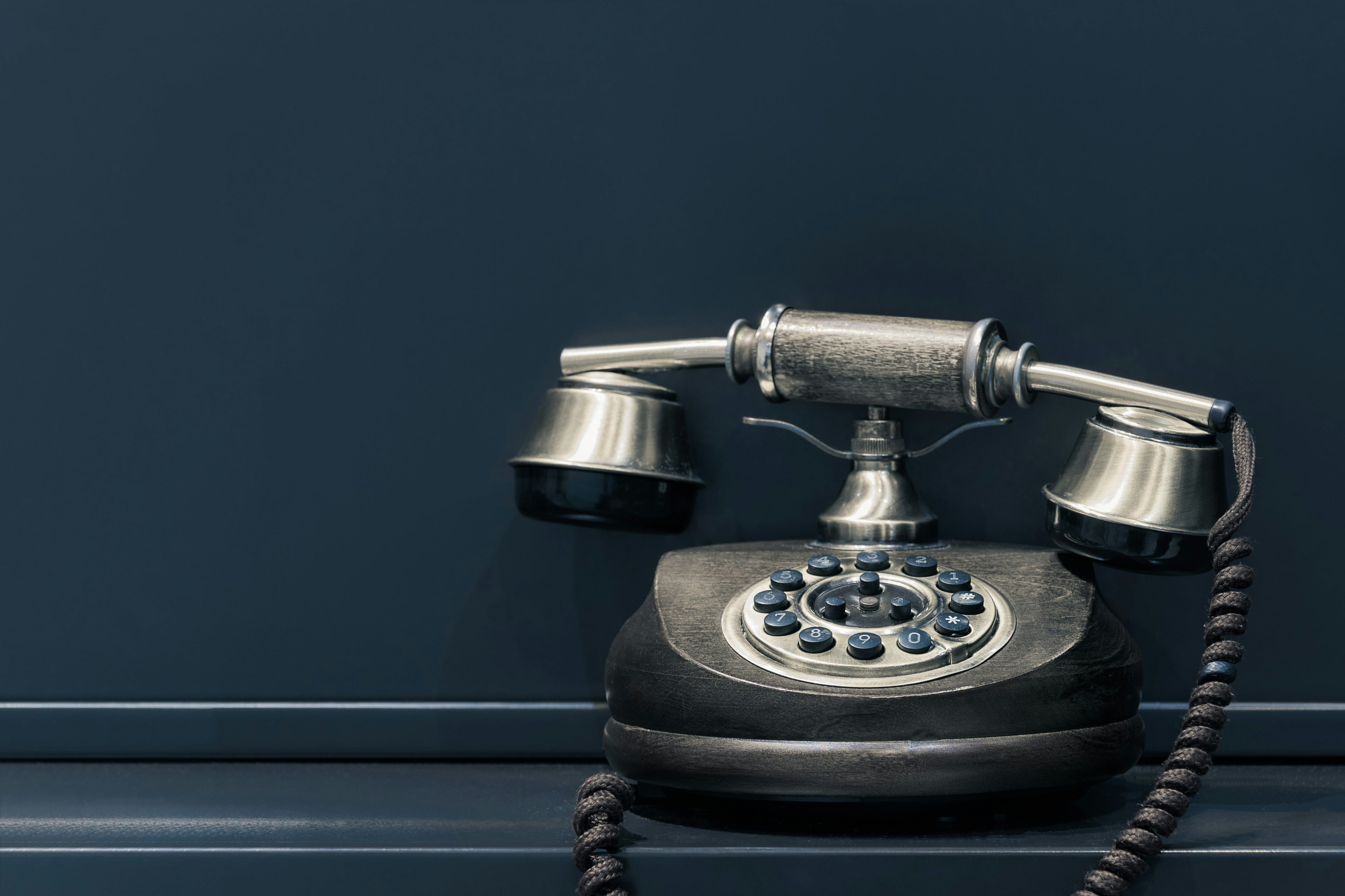 Vintage black rotary phone on a dark blue background