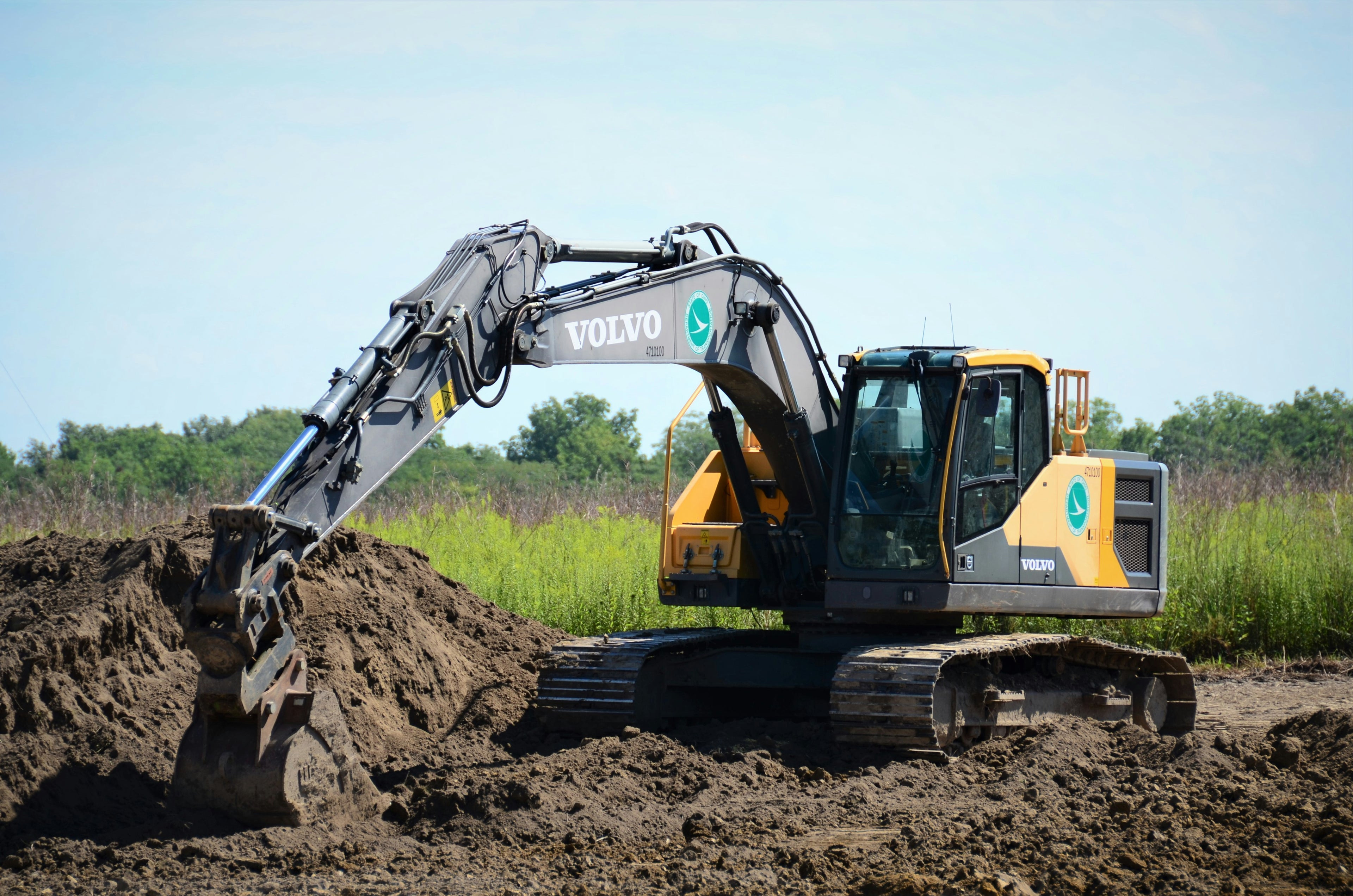Excavator digging in a field with a clear sky