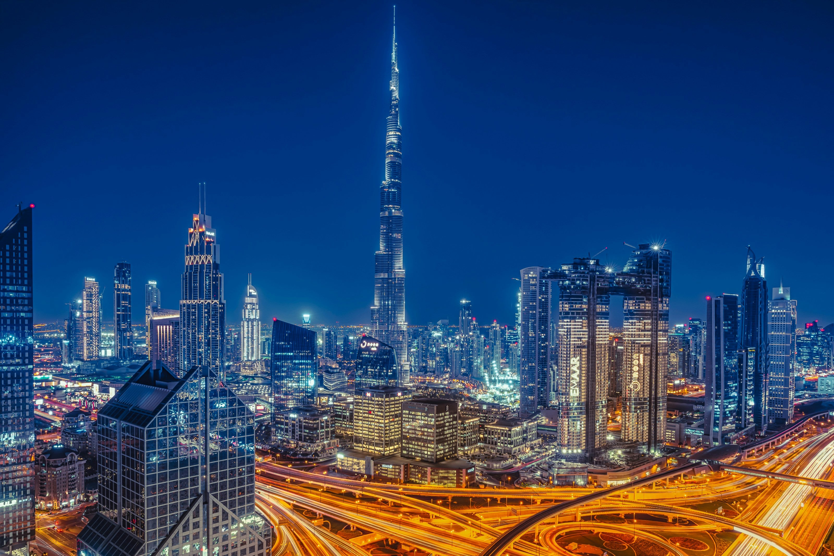 City skyline with illuminated buildings and a prominent tower at night.